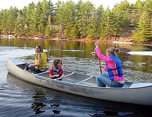 A group of girls setting off in a canoe on a l...