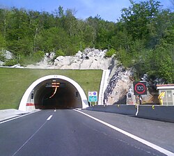 Tunelportalo kun varia trafiko subskribas indikanta-trafikfluodirekton kaj rapideclimo devigita estas videbla ĉe la tunelenirejo kaj al la flanko de la vojo