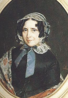 Portait en couleur d'une dame de 60 à 70 ans, brune, souriante, avec bonnet de dentelles, robe sombre et châle clair.