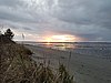 Закат над пляжем во время отлива с землей вдали