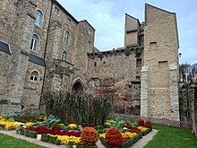 Jardin fleuri avec monument à droite et mur à l'arrière-plan