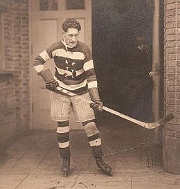 Photographie en noir et blanc d'un joueur de hockey debout avec son équipement de hockey sur glace
