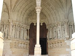 Photographie en couleurs du portail d'une église surmonté d'un tympan en ogive, colonne au premier plan.