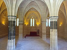 Sala Capitular del Monasterio de Piedra. Presenta 4 columnas antes policromadas, ahora descoloradas, con restos de pintura azul; al fondo, una mesa roja. Toda la sala está rodeada por un banco continuo.