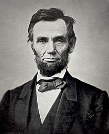 An iconic black and white photograph of a bearded Abraham Lincoln showing his head and shoulders.