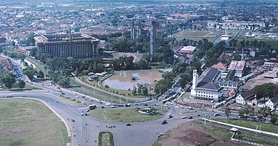 Vanaf het Nationaal Monument (Monas) in Jakarta. Links is de in aanbouw zijnde Istiqlal moskee en de kathedraal, rechts het Tugu Pembebasan Irian Barat oftewel het bevrijdingsmonument op Lapangan Banteng (het voormalige Waterlooplein). Daarachter is het Ministerie van Financiën te zien. Het ministerie is gevestigd in het voormalige Paleis van Daendels, in de koloniale tijd ook wel het "Grote Huis" genoemd. (Datum: tussen 1963 en 1980)