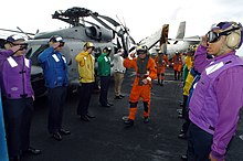 Flightdeck personnel on board an aircraft carrier wearing different colored jerseys, denoting a specific function. (U.S. Navy) (2004) Coloured flight deck jerseys.jpg