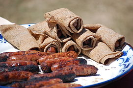 assiette dans laquelle sont disposées des saucisses cuites, et des d'autres saucisses cuites entourées de galettes de sarrasins.