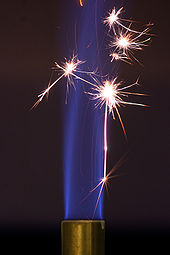 The sparks created by striking steel against a piece of flint provide the activation energy to initiate combustion in this Bunsen burner. The blue flame sustains itself after the sparks stop because the continued combustion of the flame is now energetically favorable. Incandescence.jpg