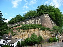 The wall of Nottingham Castle above with some cave entrances below. Tunnels beneath the castle were used by Edward III's men in the 1330 coup. Nottingham caves 01.jpg