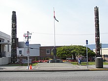 Two of the many totem poles in Prince Rupert are situated outside City Hall. Totem poles near City Hall, Prince Rupert, British Columbia.jpg