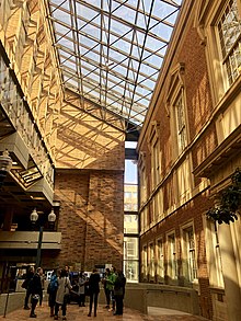 A sunny sky-lit galleria between the brick walls of two buildings.