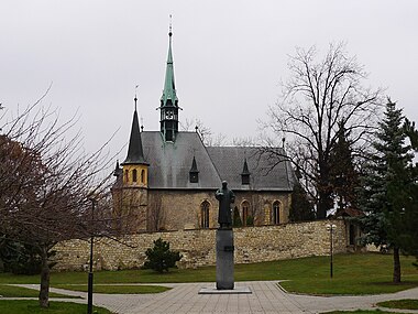 Kostel se hřbitovní zdí a sochou Benedikta Rejta