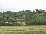 buildings surrounded by trees, fields in the foreground