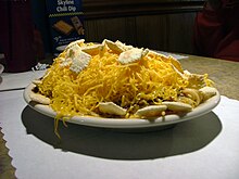 small oval white plate holding partially-eaten 5-way, showing spaghetti, sauce, cheese, and oyster crackers