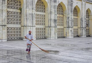 خادمُ مسجد بيت المُكرَّم يشطف جانبًا من الصحن