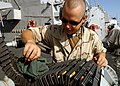 US Navy 050204-N-5345W-034 Gunner's Mate 3rd Class James Rutherford cleans the ammunition belt on a MK-38 25mm machine gun system he mans while standing port-side watch aboard the Arleigh Burke-class guided missile destroyer US.jpg