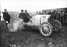 Photo d'une voiture moteur tournant dégageant un panache de fumée avec son pilote au volant.