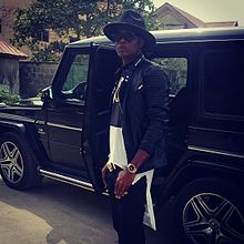 Young man in a fedora hat beside a g wagon