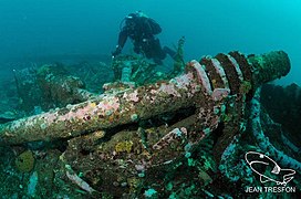 Diver swimming over a clump of wreckage near the boiler