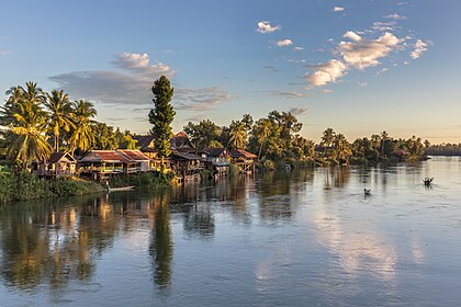 Margem do rio Mecom com habitações de palafitas, árvores e nuvens na hora dourada, vista da ponte entre Don Det e Don Khon, Si Phan Don, Laos. O Mecom é um rio principal no Sudeste Asiático que atravessa seis países. Seu comprimento é de 4 350 km a 4 909 km. Isto o torna um dos doze maiores rios do mundo. (definição 5 381 × 3 588)