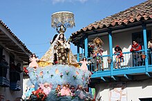 A saqra (animal figure) dancer watching the procession of Mamacha Carmen from a balcony Virgen del Carmen - Paucartambo Peru.jpg