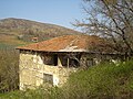 Стара македонска куќа со низи везени пиперки, во позадина се гледа разрушената селска црква