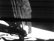 A mounted slowscan TV camera shows Neil Armstrong as he climbs down the ladder to surface.