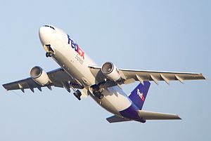 A FedEx Airbus A300 with condensation in both intakes, with its gear retracting.