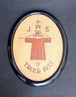 Panneau d'intarsia commémorant l'édition 1933 du pèlerinage de la Sainte Tunique en la cathédrale Saint-Pierre de Trèves. L'image de la relique est surmontée du monogramme JHS. (définition réelle 1 657 × 2 117)