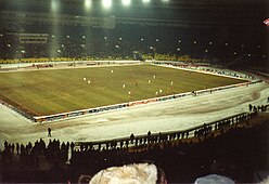 Football match with snow covering the stadium lanes and spectators wearing winter gear