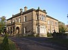 A stone house in two storeys, with an entrance portico and a two-story bay window