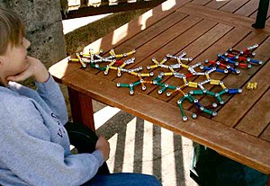 Мальчик с синдромом Аспергера, играющим с молекулярными структурами.