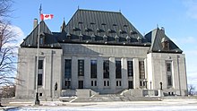 Large grey building in winter, with a Canadian flag in front