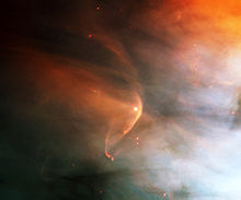 Пятнистая оранжево-голубая туманность на черном фоне с изогнутой оранжевой дугой, огибающей звезду в центре.
