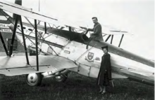 Photographie noir et blanc d'un homme debout dans le cockpit d'un avion et d'une femme, debout, appuyé contre le fuselage.