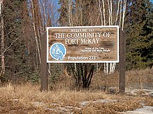 Un panneau brun devant des bouleaux, il souhaite la Bienvenue dans la communauté Fort McKay.