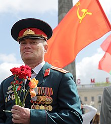 A member of the Armed Forces of Belarus on Victory Day in 2014 under the Soviet flag. General s vlajkou v pozadi - panoramio.jpg