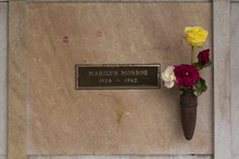 عکسی از گورابهٔ مونرو، گرفته‌شده در ۲۰۰۵. «مریلین مونرو، ۱۹۲۶–۱۹۶۲» روی یک لوح یادبود نوشته شده‌است. گورابه دارای مقداری اثر رژ لب از بازدیدکنندگان است و گل‌ها در گلدانی متصل به گورابه قرار داده شده‌اند.