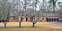 A brick home with brown trim and a large lawn in front.