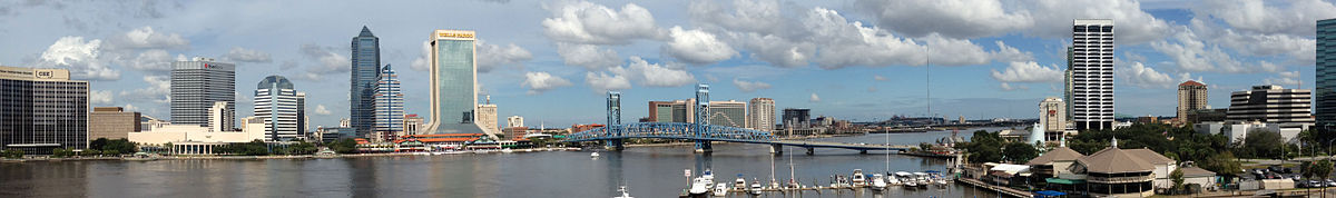 A city with several tall buildings and a bridge spanning the river, running in front of the buildings