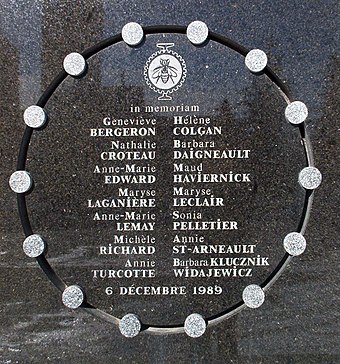 commemorative plaque in polished stone, deeply engraved with in circle with 14 small silver disks distributed around the circle. Inside, and under the university's logo and the legend "In Memoriam" are the names of the 14 victims and the date of the massacre