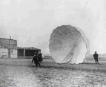 Albert Berry collapses his parachute on Kinloch Field at Jefferson Barracks, Missouri, after his jump on 1 March 1912. Albert Berry parachute.jpg