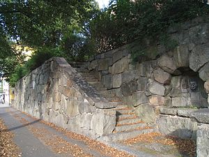 Parti av stödmuren och valvet mellan två av trapporna och maskaronen av sten sitter under valvet.