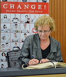 A woman signs a minute book on the stage of public meeting