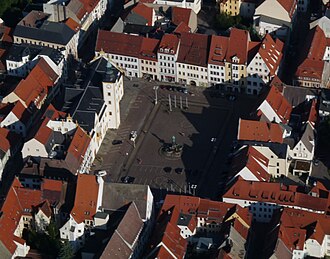 Barevná fotografie s pohledem z výšky na náměstí s pravidelným čtvercovým půdorysem