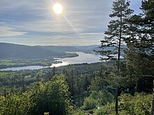 Foto eines Sees in einer hügligen und bewaldeten Umgebung