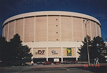 Exterior view of a tall circular building colored in beige and white