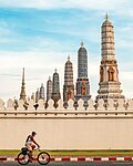 A man cycling outside the wall of the Grand Palace, Bangkok - Thailand, by Kriengsak Jirasirirojanakorn