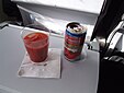 Verre de jus de tomate avec sa canette, sur la tablette d’un siège d’avion.